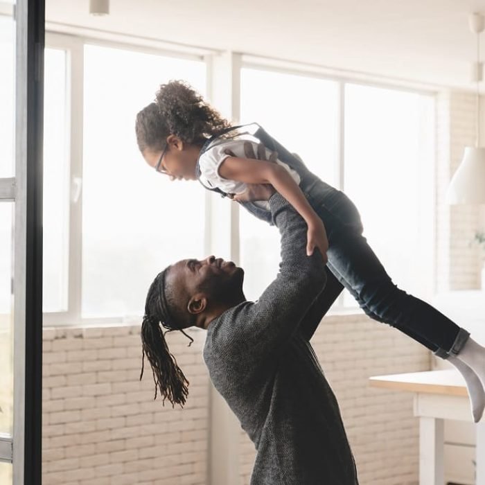 Happy young african-american father dad having fun with small preteen daughter, playing games together at home. Fatherhood concept. Happy Father`s day! Family bonding moments